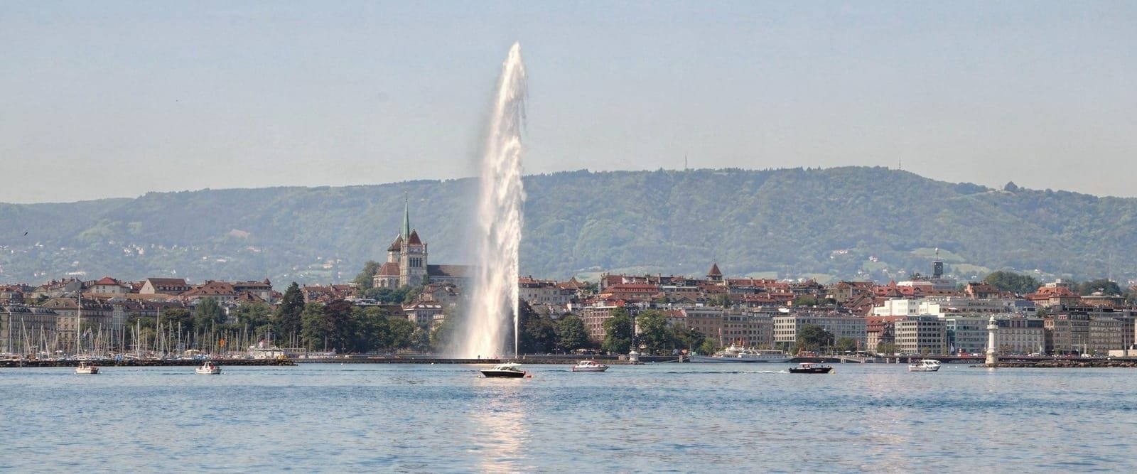 The Jet d’Eau and the Geneva Old Town skyline, photographed from the shores of Lake Geneva on a clear morning.